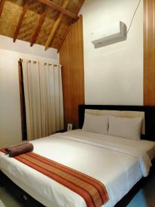 een slaapkamer met een groot wit bed en een licht bij Tania Homestay in Bumbang