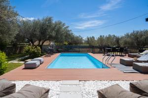 een zwembad in een achtertuin met stoelen en een tafel bij Villa Sorina Kefalonia in Svoronata