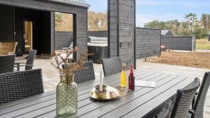 einen Holztisch mit einer Vase auf einer Terrasse in der Unterkunft Villavilla #621 - Dueodde, Bornholm in Vester Sømarken