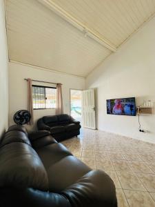 ein Wohnzimmer mit einem Ledersofa und einem Flachbild-TV in der Unterkunft Casa Bombinhas Bombas beach in Bombinhas