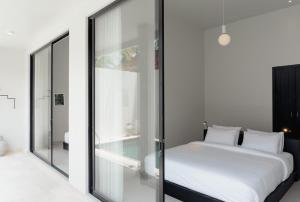 a bedroom with a white bed and a glass wall at Villa IKIN in Lovina +38 photos