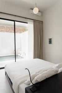 a white bedroom with a large bed and a window at Villa IKIN in Lovina