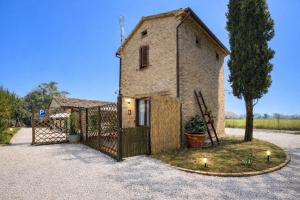 een stenen huis met een poort en een boom bij fattoria Coppetella Cemani in Molino dʼAgugliano