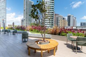 een patio met een tafel en stoelen en een boom bij ICON - Vista Mar Boa Viagem in Recife