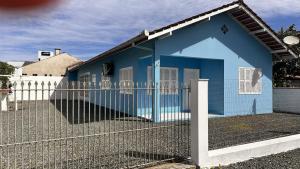 ein blaues Haus mit einem Zaun davor in der Unterkunft Casa ampla no centro Barra Velha in Barra Velha