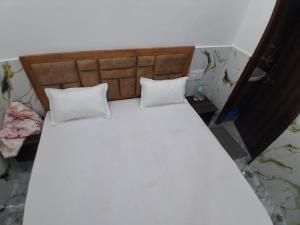ein großes weißes Bett mit zwei Kissen darauf in der Unterkunft Prabhu Kripa Dham Guest House in Jāmb