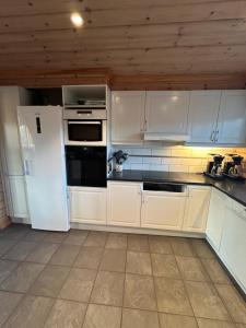 een keuken met witte kasten en een witte koelkast bij Holmfoss Hytta in Larvik