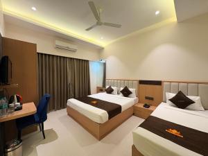 a hotel room with two beds and a desk at Hotel JK Palace Newly Renovate in Shirdi
