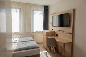 ein Schlafzimmer mit einem Bett und einem Schreibtisch mit einem Fernseher in der Unterkunft acama Hotel & Hostel Kreuzberg in Berlin