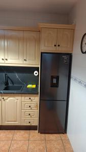 una cucina con frigorifero nero e armadietti in legno di La Osera ad Arroyo Frio