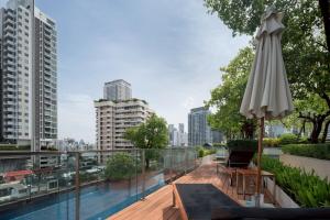 een balkon met een parasol en een zwembad bij 2BR2BA BTS Thonglor Rooftop Pool Gym BBQ Low in Bangkok