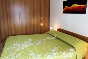 a bedroom with a bed with a green comforter at Appartamenti Rosanna in Grado
