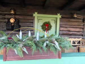 a christmas wreath on a front porch of a log cabin at Clop&Cojoc Rustic old wooden house in Bocicoiel +6 photos