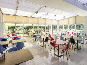 eine Cafeteria mit Tischen und Stühlen und Fenstern in der Unterkunft Ibis Gaziantep in Gaziantep