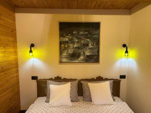 a bedroom with a bed with two lights on the wall at Clop&Cojoc Rustic old wooden house in Bocicoiel
