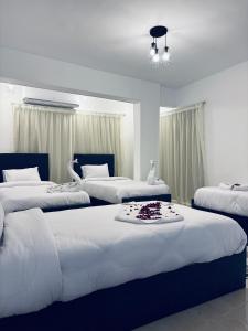 3 Betten in einem Zimmer mit weißen Wänden in der Unterkunft New Arena pyramids VIEW in Giza