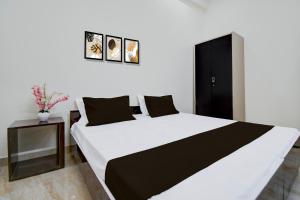 a bedroom with a large white bed and a black cabinet at HOTEL O SAV INN in Bhauli