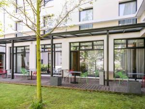 ein Gebäude mit einer Terrasse mit Tischen und Stühlen in der Unterkunft Mercure Amiens Cathédrale in Amiens