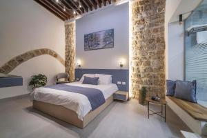 een slaapkamer met een groot bed en een stenen muur bij Soor in Akko
