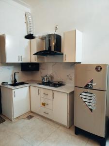 a small kitchen with white cabinets and a refrigerator at Family Signature Residency in Lahore +66 photos