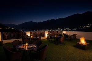 麦罗肯机The Grand Him Queen-Centrally Heated & Air Cooled # Near Mall Road # Big Parking # Spacious Rooms # Most Awarded # Property Of The Year #的带桌椅和火坑的露台