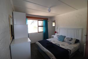 een kleine slaapkamer met een bed en een raam bij Shalom House in Arniston