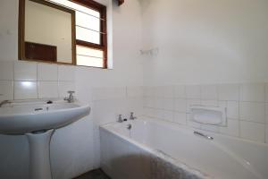 een badkamer met een wastafel, een bad en een spiegel bij Shalom House in Arniston