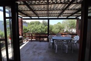 een terras met een tafel en stoelen op een balkon bij Shalom House in Arniston