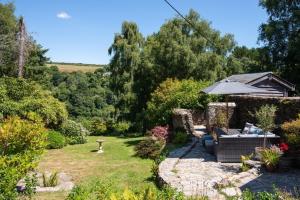 a garden with a bench and an umbrella at Hansel Cottage in Dartmouth