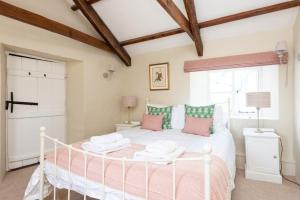 a bedroom with a white bed with pink and green pillows at Hansel Cottage in Dartmouth