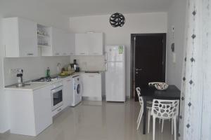 a kitchen with white appliances and a table and chairs at White Suit Apartment in Kyrenia