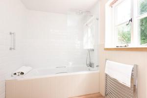 a white bathroom with a tub and a window at Hansel Cottage in Dartmouth +31 photos