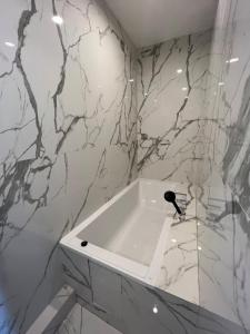 bagno con vasca bianca e pareti in marmo di Panoramic Balcony Apartment a Varsavia