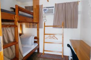 a room with two bunk beds and a desk at Pugad Hostel, El Nido in El Nido
