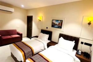 a hotel room with two beds and a red couch at Hotel Supreme Inn in Varanasi