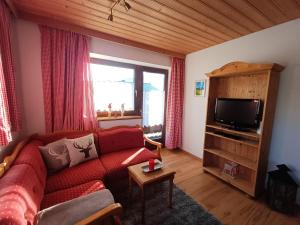 een woonkamer met een rode bank en een tv bij Ferienwohnung Schösserhof in Reith bei Kitzbühel