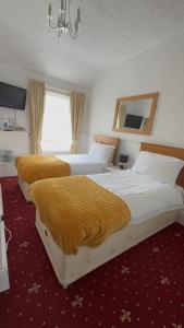 2 bedden in een hotelkamer met gele dekens bij No 34 Vance Road in Blackpool
