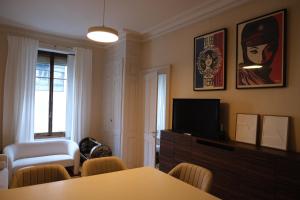 ein Wohnzimmer mit Fernseher und Tisch und Stühlen in der Unterkunft Magnificent two bedroom apartment in a luxury building in Genf