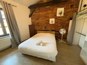 a bedroom with a bed in a room with a brick wall at L Experience Bressane 2 in Saint-Trivier-de-Courtes