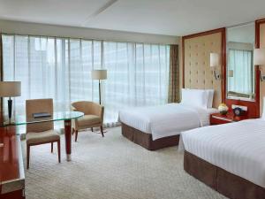 a hotel room with two beds and a desk at Pullman Shanghai Central in Shanghai