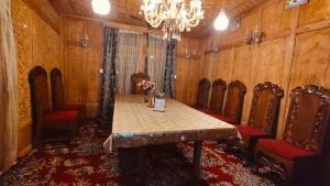 a dining room with a table and chairs and a chandelier at Heritage Houseboat - Almost Heaven in Srinagar