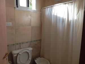 ein Badezimmer mit Toilette und Duschvorhang in der Unterkunft Tacuarita in Los Hornillos