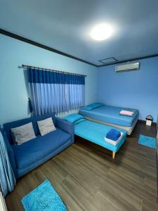 een kamer met 2 blauwe bedden en een bank bij Sea Side Villa in Ban Pak Khlong Cha-am