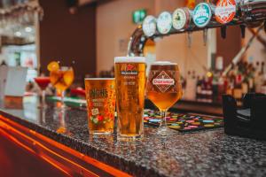 drie glazen bier zittend op een bar bij Draycote Hotel And Whitefields Golf Course in Rugby