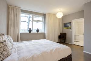 een slaapkamer met een groot wit bed en een raam bij Appartementen Ossegang in Uithuizen