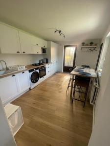 een keuken met witte kasten, een tafel en een fornuis bij Le Jardin de Phanie, le calme de la campagne en ville in Metz +4 foto's