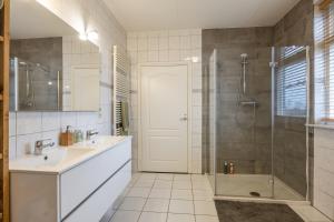 een badkamer met een douche, een wastafel en een bad bij Appartementen Ossegang in Uithuizen