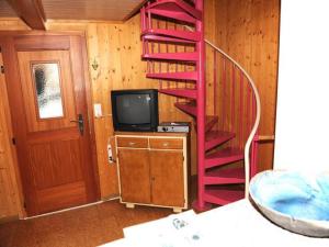 a red spiral staircase in a room with a tv at wooden chalet in Betten near the Aletsch Arena in Betten