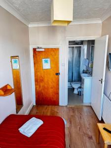 een slaapkamer met een rood bed en een houten deur bij Ambassador Hotel in Brighton & Hove