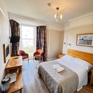 een hotelkamer met een bed, een bureau en een televisie bij Ambassador Hotel in Brighton & Hove